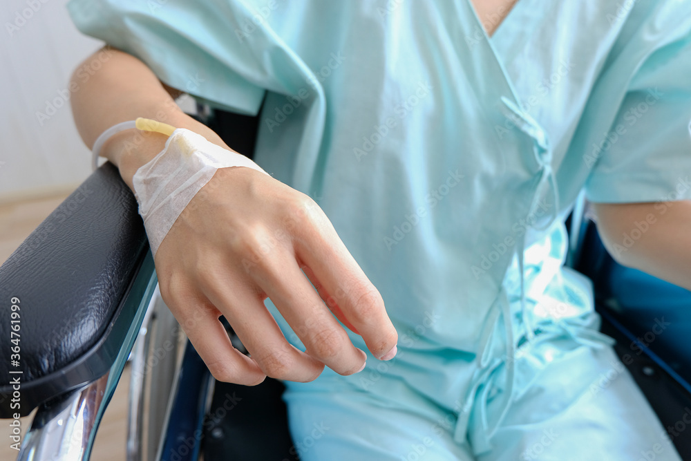 Close up of saline drip in patient's hand in hospital admission, hand had injection plug for injecting fluid drug seat on a wheelchair,Healthcare and medically concept. Close up of saline drip in patient's hand in hospital admission, hand had injection plug for injecting fluid drug seat on a wheelchair,Healthcare and medically concept.