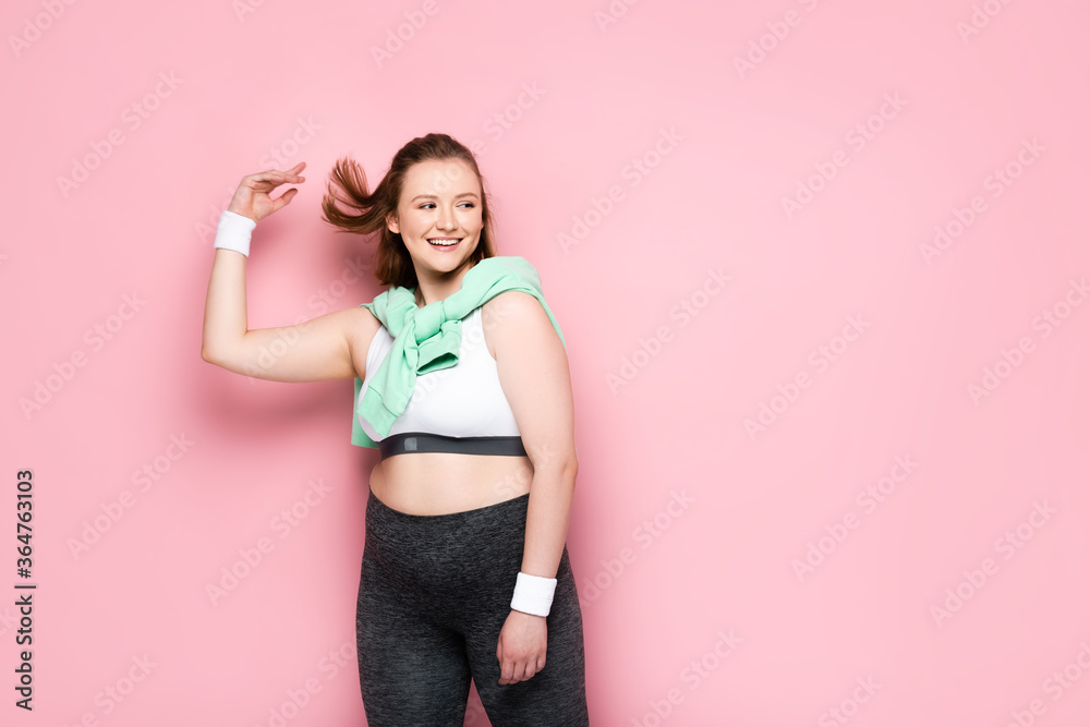 happy overweight girl with sweatshirt over shoulders looking away on pink happy overweight girl with sweatshirt over shoulders looking away on pink