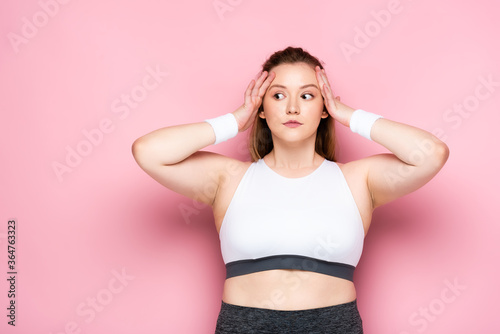 shocked overweight girl touching head and looking away on pink © LIGHTFIELD STUDIOS