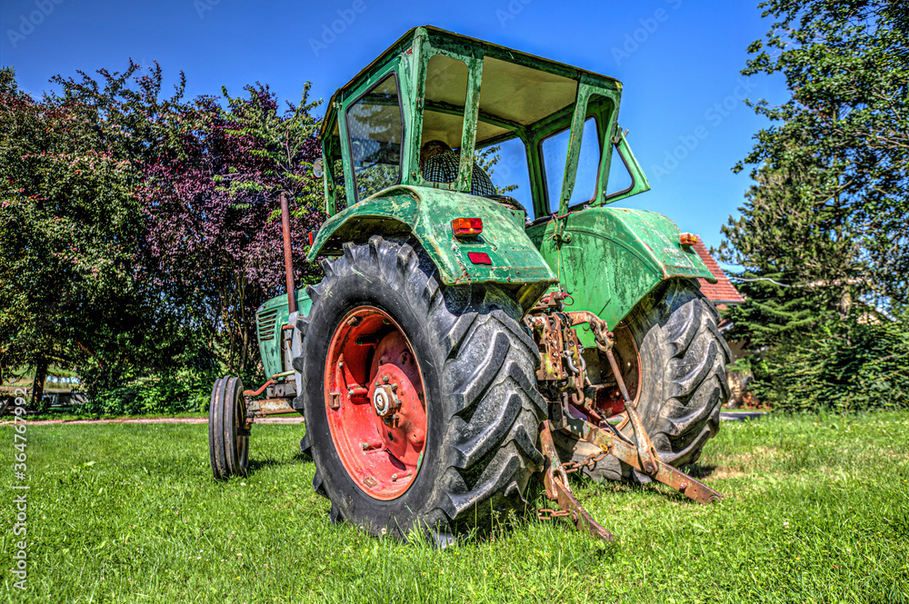 Obraz premium A German vintage tractor stands on a green meadow