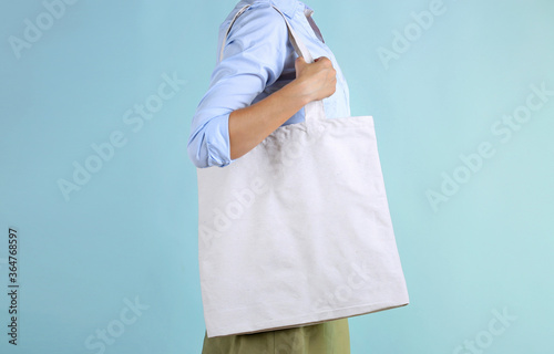 Woman holding textile bag in hands on blue background,person with fabric tote.Shopping concept