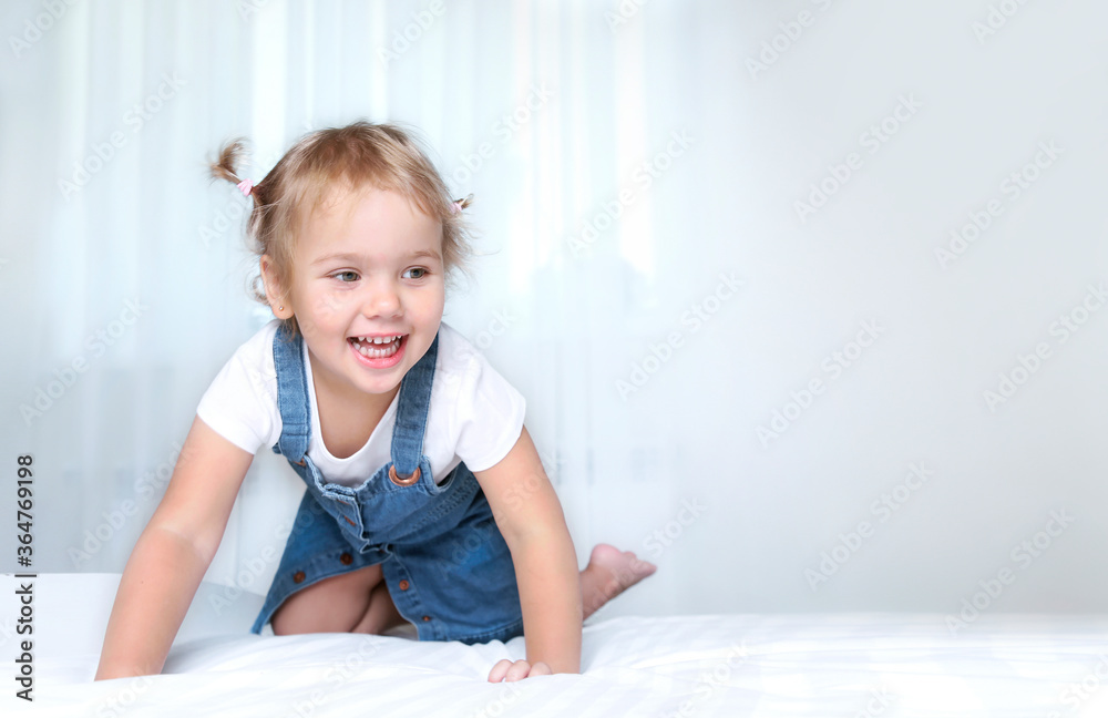 Child on a bed empty copy space background.Girl in white sheet in bedroom.Happy kid jumping on bed. Child on a bed empty copy space background.Girl in white sheet in bedroom.Happy kid jumping on bed.