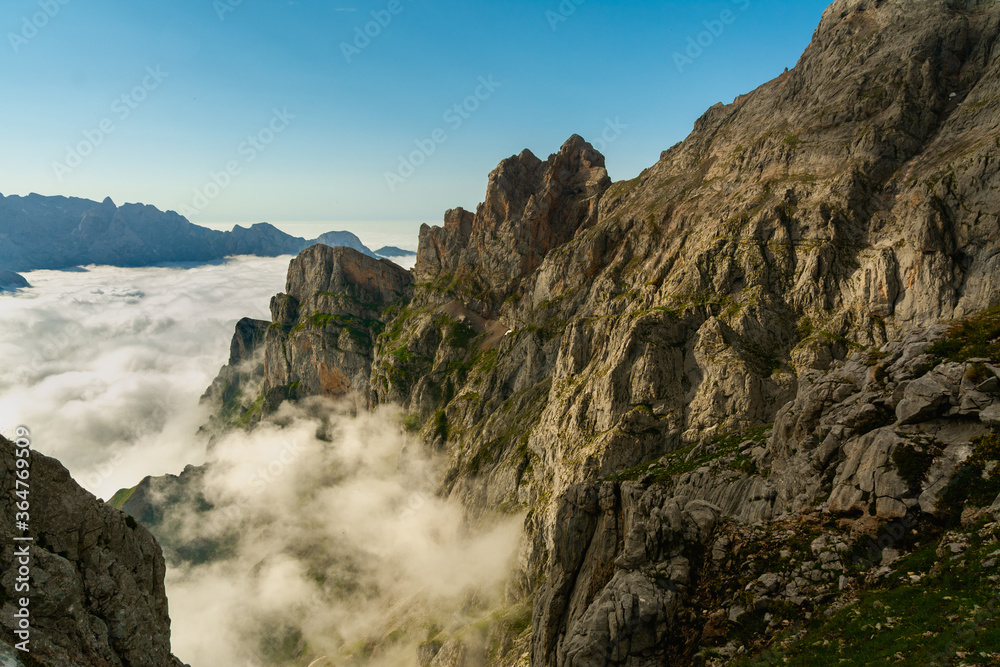 Fototapeta premium Luces de atardecer en las montañas de los Picos de Europa con un mar de nubes y el cielo azul