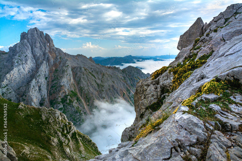 Obraz premium Mar de nubes entre las montañas de los Picos de Europa, con la Torre de El Friero a la izquierda y el Valle de Valdeón cubierto con nubes con un cielo azul nublado