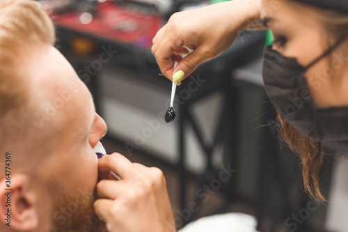 Removing hair from the nose with wax in barbershop, male beauty and care concept