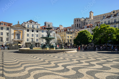 Rossio Square or Pedro IV Square (Praça de D. Pedro IV) with fountain, typical portuguese cobblestone hand-made mosaic pavement, ruins and buildings in the background, in Lisbon, Portugal