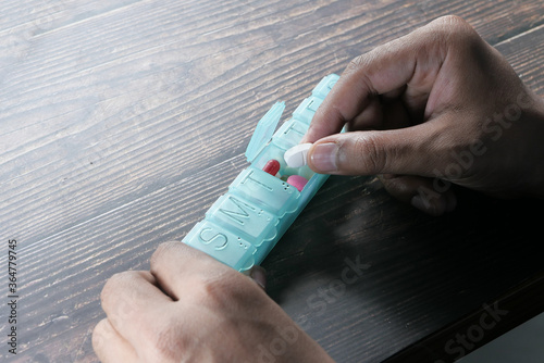 Close up of man hand taking pills from pill box  photo