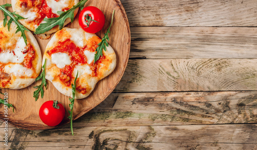 Pizzete. Home baked mini pizzas bolognese. Tomato sauce ,mozzarella cheese and minced meat. Rustic wooden table. Stay at home concept photo