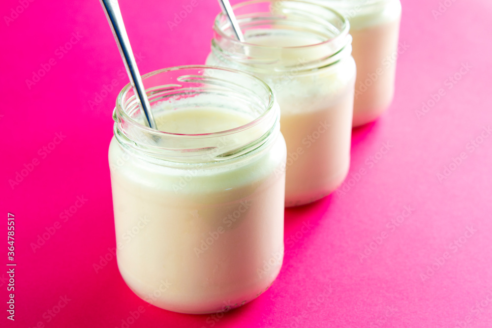 Three glasses of creamy yogurt on pink background Three glasses of creamy yogurt on pink background