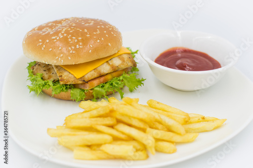 Grilled chicken burger with ketchup and fries on the side. 