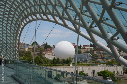 Glass bridge of peace in the capital of Georgia-Tbilisi. The white ball is an attraction. It lifts people 150 meters above the city. July 2020