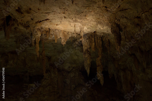 Natural texture. Geology. Closeup of the rock surface and stalactites inside a dark cave. 