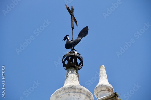 Rooster and Catholic cross on steeple of old church
