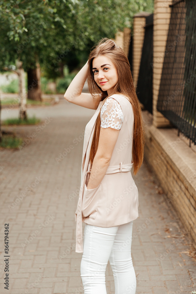 Photosession of a pretty girl walking in the city at sunset in casual style with beautiful hair