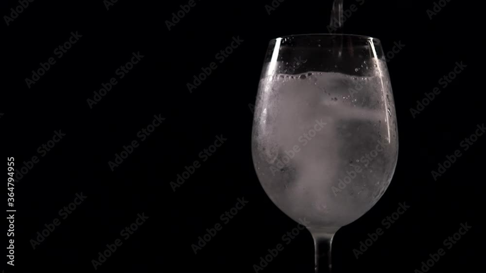 Bubbles and bubbling foam of fizzy drink in wine glass over black background. Soda beverage pour into transparent glass slow motion close up view Bubbles and bubbling foam of fizzy drink in wine glass over black background. Soda beverage pour into transparent glass slow motion close up view