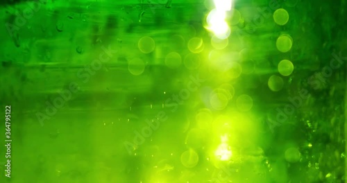 Water drops on green glass, blurred background. Glare of light, sun. Texture
