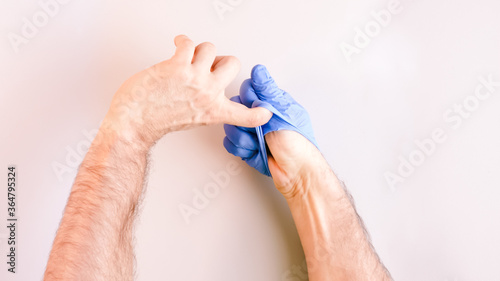 Image 7 of a sequence of images in which a man's hands taking off blue disposable gloves medical. Top view. Selective focus