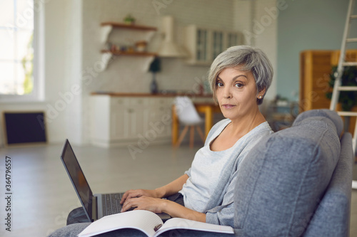 Mature woman with laptop working online from home.