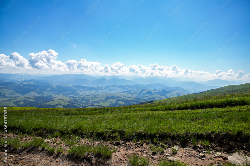 Beautiful dramatic white clouds on blue sky over green Carpathian mountains. Tops of the Carpathian mountains. Beautiful landscape with greenery and clouds.