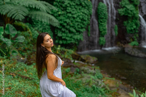 Girl walks in a white dress on a background of a waterfall.