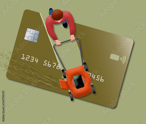A man uses his lawn mower to cut up a huge credit card. View is from above looking down. .