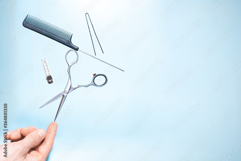 Had holding flying hairdresser tools comb, scissors under trendy color background with copy space and soft light. Stylish Professional Barber Scissors, Hairdresser salon concept, Haircut accessories.