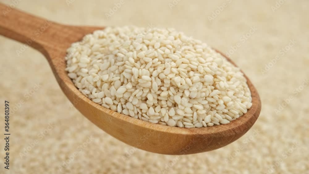 sesame seeds in wooden spoon and on background rotating. top view sesame seeds in wooden spoon and on background rotating. top view