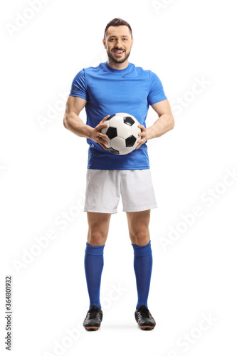 Soccer player holding a ball and looking at the camera