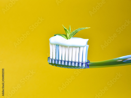 Toothbrush and toothpaste on a yellow background  a leaf of mint. 