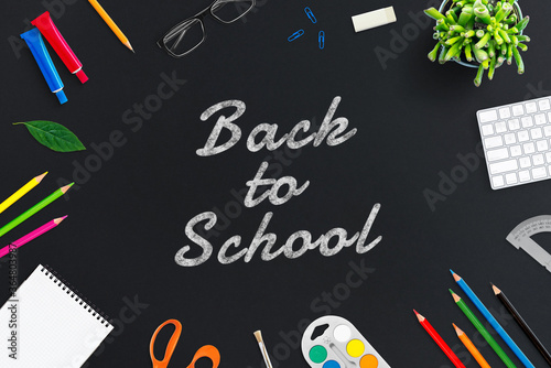 Back to school text on chalkboard desk surrounded by school supplies. Flat lay, top view composition