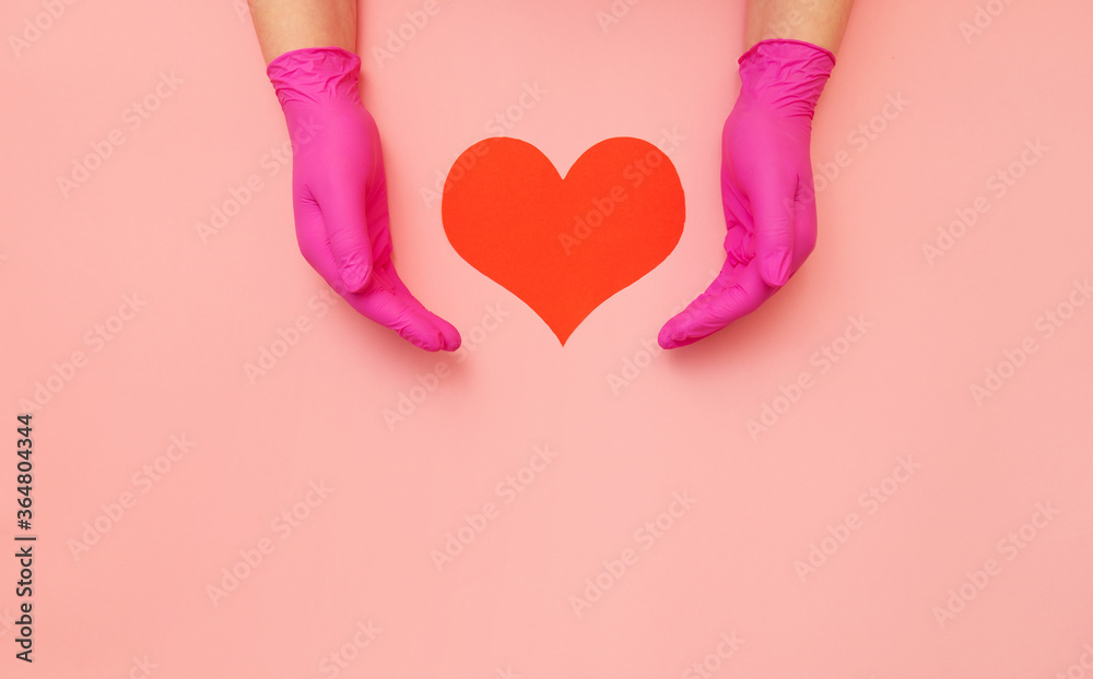 Close-up of hands in pink protective hold red heart. Cardiology concept.