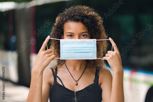 Φωτογραφία Young woman showing mask in front of her face against covid