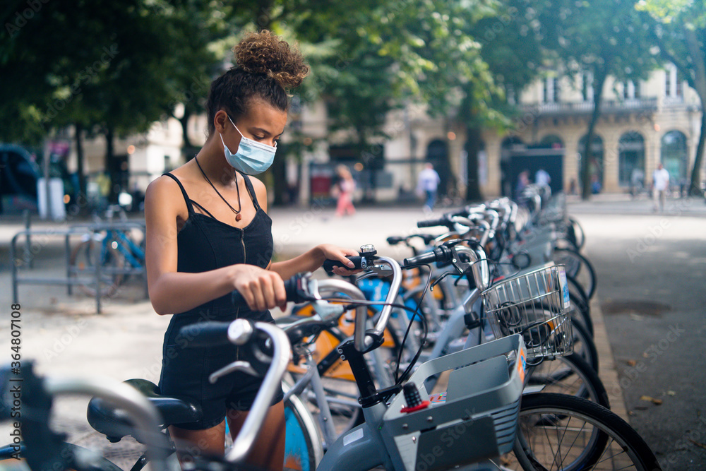 Obraz premium Young beautiful woman renting a bicycle in the city