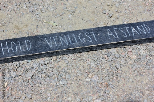 Wooden sign with inscription: Please keep your distance, hold venligst afstand, denmark