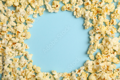Circle made of popcorn on blue background. Food for cinema