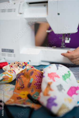 Woman sewing homemade fashion cotton fabric masks at home