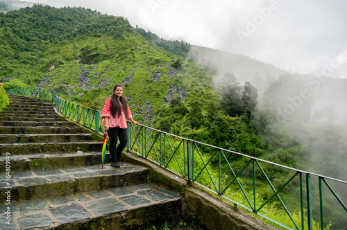 Young indian girl in a red dress standing on a series of stairs leading to the bhagsu falls in McLeodganj in himachal india photo