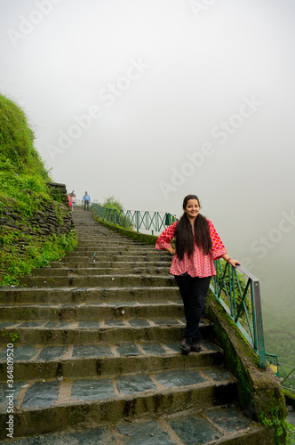 Young indian girl in a red dress standing on a series of stairs leading to the bhagsu falls in McLeodganj in himachal india photo