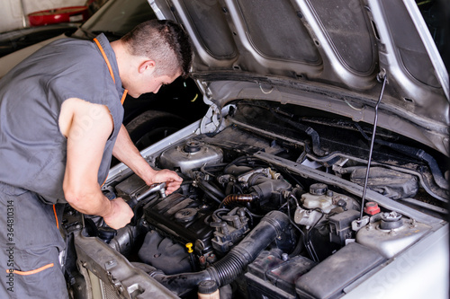 Mechanic working with a wrench on the car engine.