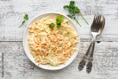Photos Fresh coleslaw salad from shredded cabbage, carrot and mayonnaise on white wooden table
