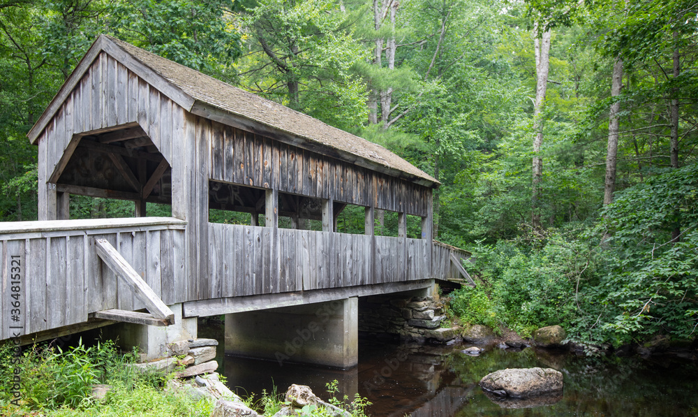 Wooden Covered bridge over a small river in a lush green forest at Devil's Hopyard State Park