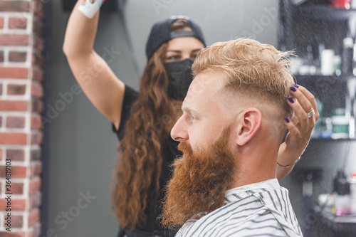 Hair styling in women barbershop. Spray