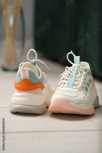 White women's sneakers lying on the floor alone