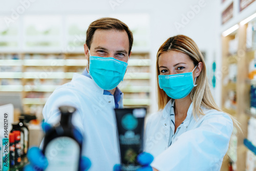 Male and female pharmacists with protective mask on their faces working at pharmacy. Medical healthcare concept.
