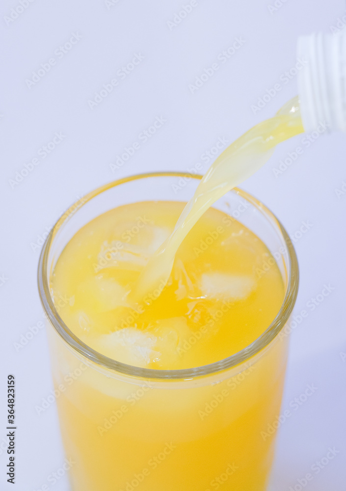 Pouring orange juice from bottle into glass with splashing Pouring orange juice from bottle into glass with splashing