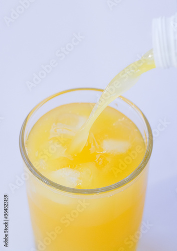 Pouring orange juice from bottle into glass with splashing