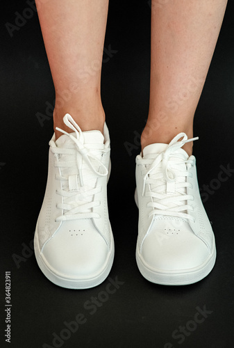 White women s sneakers dressed by a girl on a black background