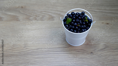 Bild auf Leinwand bucket of American blueberries in a white bucket on a wooden table