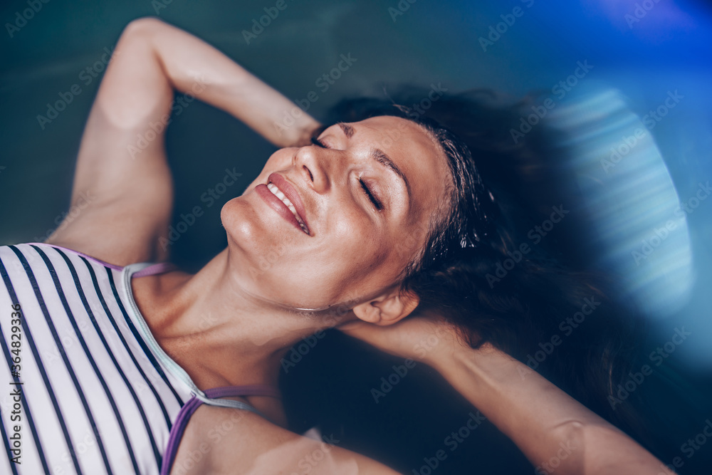 Beautiful pregnant woman floating in tank filled with dense salt water used in meditation, therapy, and alternative medicine. Beautiful pregnant woman floating in tank filled with dense salt water used in meditation, therapy, and alternative medicine.