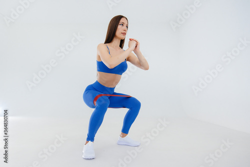 Sexy young girl performs sports exercises on a white background. Fitness, healthy lifestyle